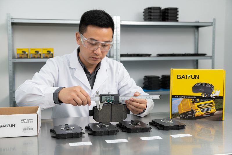 Техник BAIYUN Brake проверяет фрикционный материал и коды на торце тормозной колодки для коммерческого автомобиля в лаборатории контроля качества.